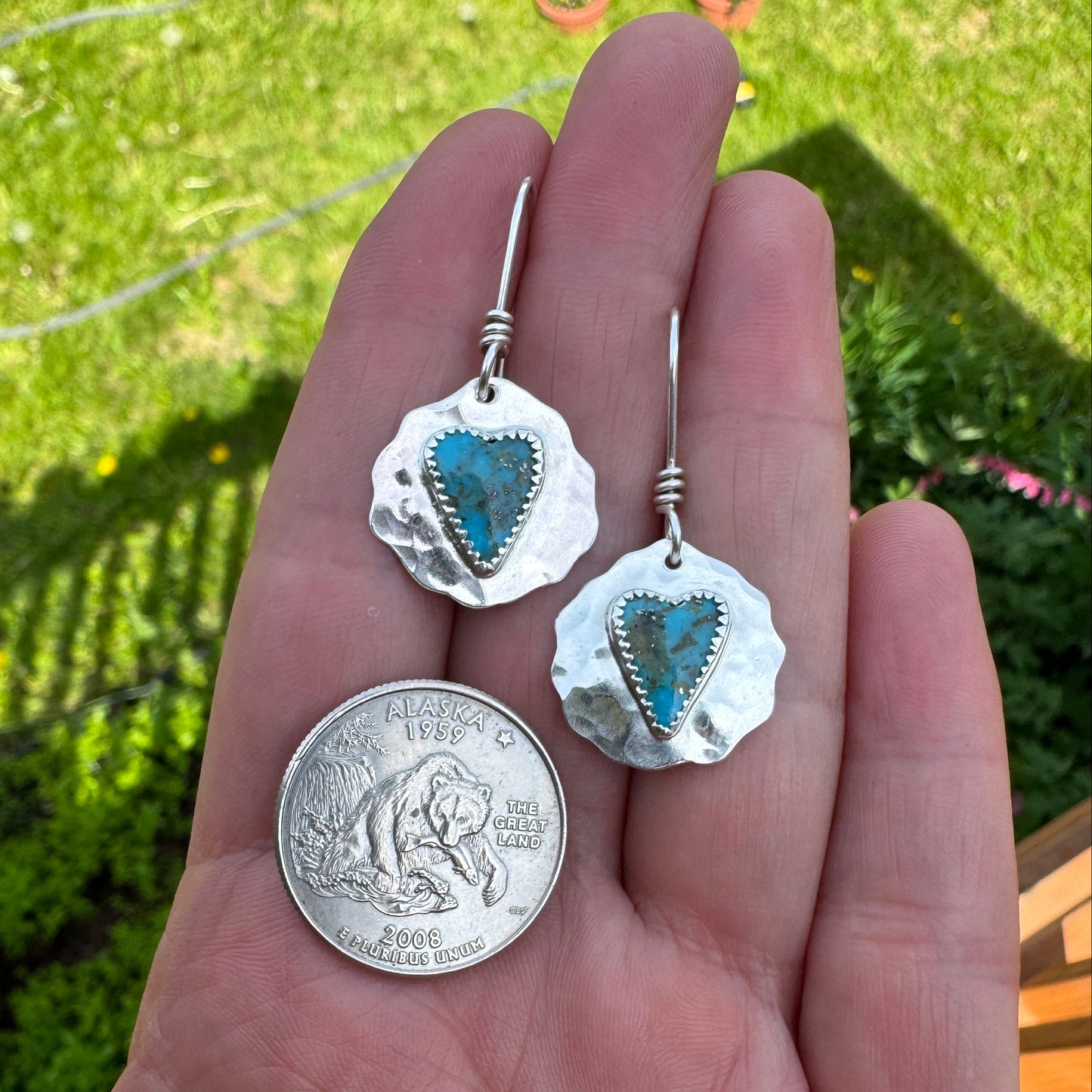 Close-up of slim heart-shaped Kingman turquoise bezel set in sterling silver with Alaska stat quarter for size reference.